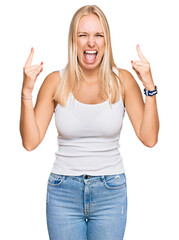 Fototapeta na wymiar Young blonde girl wearing casual style with sleeveless shirt shouting with crazy expression doing rock symbol with hands up. music star. heavy music concept.