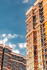 Fototapeta premium Multi-storey residential building. A newly built residential complex. The concept of urban construction. View of a multi-storey building against a blue sky background. Vertical image.