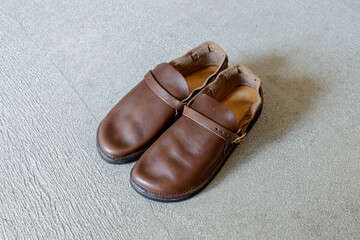 コンクリートの床に置かれた茶色の革靴,レザーシューズ