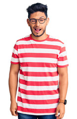 Handsome latin american young man wearing casual clothes and glasses winking looking at the camera...