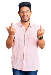Handsome latin american young man wearing casual summer shirt showing middle finger doing fuck you...