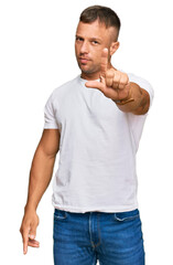 Handsome muscle man wearing casual white tshirt pointing with finger up and angry expression, showing no gesture