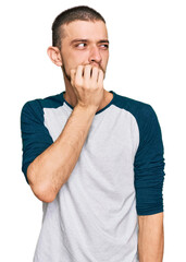 Hispanic young man wearing casual clothes looking stressed and nervous with hands on mouth biting nails. anxiety problem.