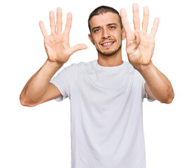 Hispanic young man wearing casual white t shirt showing and pointing up with fingers number nine while smiling confident and happy.