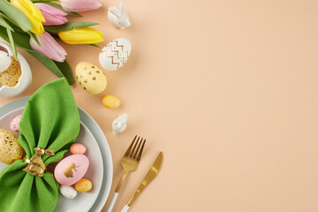 The Easter table is set with festive elegance. Top view photo of plates, cutlery, green napkin,...