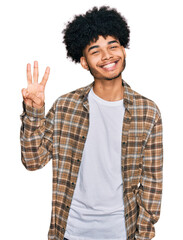 Young african american man with afro hair wearing casual clothes showing and pointing up with fingers number three while smiling confident and happy.