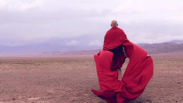 A monk in red prays in the steppe. A divine ritual.