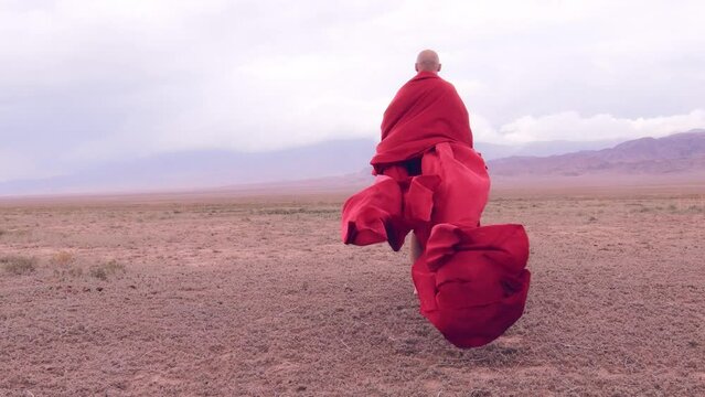 A monk in red prays in the steppe. A divine ritual.