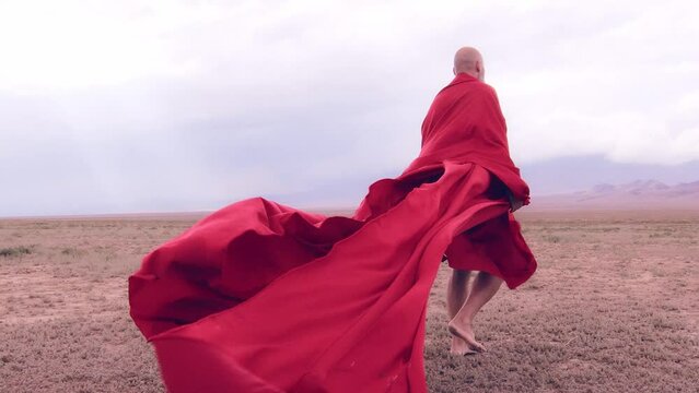 A monk in red prays in the steppe. A divine ritual.