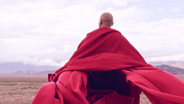 A monk in red prays in the steppe. A divine ritual.