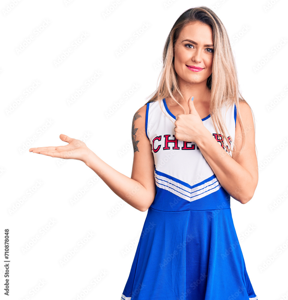 Sticker Young beautiful blonde woman wearing cheerleader uniform showing palm hand and doing ok gesture with thumbs up, smiling happy and cheerful