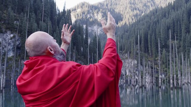 A monk in red prays in the steppe. A divine ritual.