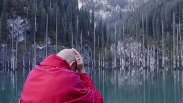 A monk in red prays in the steppe. A divine ritual.