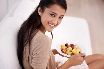 Happy woman, portrait and bowl of fruit salad for diet, nutrition or healthy snack on sofa at home. Face of young female person, nutritionist or vegan smile and eating breakfast for vitamin c or meal