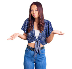 Young beautiful chinese girl wearing casual clothes clueless and confused expression with arms and...