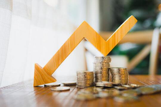 A pile of money and a arrow pointing down symbolizes falling currency and falling interest rates, concepts of inflation and deflation.