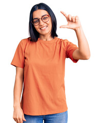 Young beautiful latin woman wearing casual clothes smiling and confident gesturing with hand doing small size sign with fingers looking and the camera. measure concept.