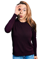 Young caucasian woman wearing casual clothes doing ok gesture shocked with surprised face, eye looking through fingers. unbelieving expression.
