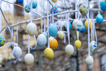 Colorful handmade egges for easter in branches outdoor. Decorating trees with hanging eastereggs in...