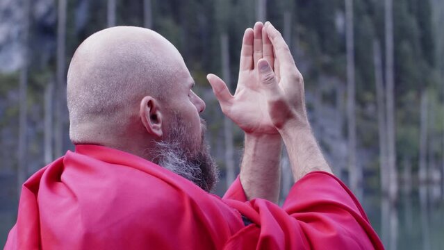 A monk in red prays in the steppe. A divine ritual.