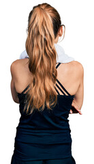 Naklejka premium Young caucasian woman wearing sportswear and towel standing backwards looking away with crossed arms