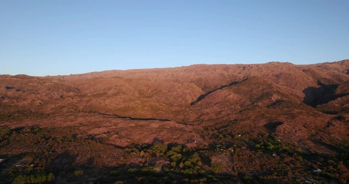 Aerial drone scene of orange sunset over rocky mountain river between woody landscape.Golden hour in mina Clavero, Cordoba, Argentina