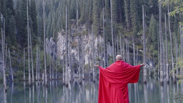 A monk in red prays in the steppe. A divine ritual.
