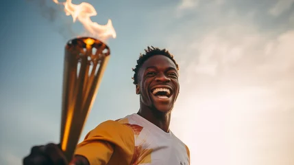 Poster Im Rahmen A happy smiling athlete, a black man, solemnly carries the Olympic flame against the sky © Vadim