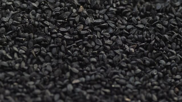 close-up black cumin seeds heap rotation. slow motion. macro heap black cumin seeds