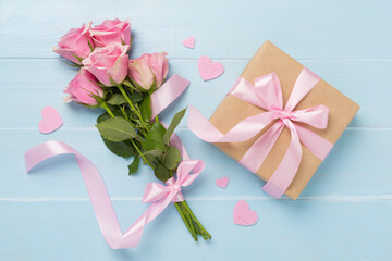Pink roses with hearts and gift box on wooden background, top view. Valentines day concept