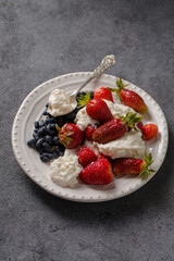 Milk dessert with strawberries and honeysuckle on a white plate