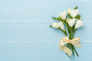 White freesia flower on wooden background, top view