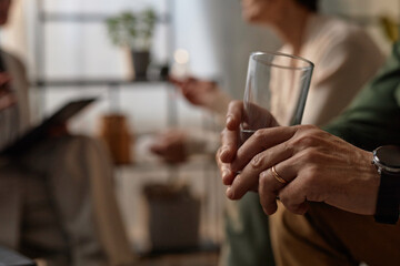 Side view of unrecognizable man holding glass of water in couples therapy session, copy space