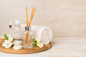 Spa composition with freesia flower and aroma diffuser on wooden table
