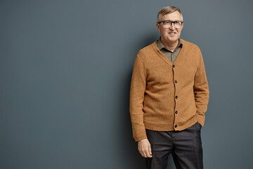 Front view portrait of mature man wearing glasses and looking at camera standing against grey background, copy space