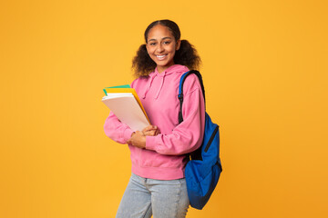 black teen girl student posing with backpack and notebooks, studio