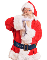 Old senior man with grey hair and long beard wearing traditional santa claus costume doing time out...
