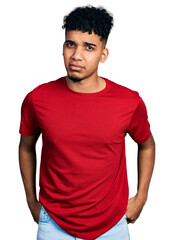 Young african american man wearing casual red t shirt skeptic and nervous, frowning upset because of problem. negative person.