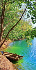 Fototapeta premium A small fishing boat with oars near the shore on a wonderful emerald lake.