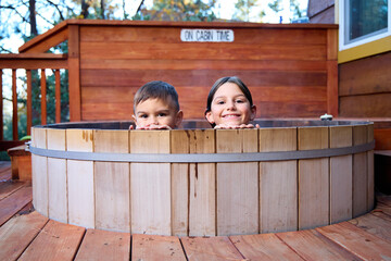 Young kids soak in a hot tub on a porch