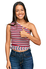 Beautiful hispanic woman wearing casual clothes doing happy thumbs up gesture with hand. approving expression looking at the camera showing success.