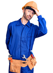 Young hispanic man wearing worker uniform surprised with hand on head for mistake, remember error....
