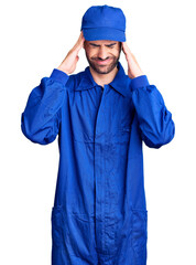 Young hispanic man wearing painter uniform suffering from headache desperate and stressed because pain and migraine. hands on head.