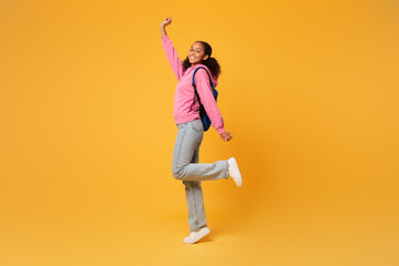black student girl posing with blue backpack over yellow background - obrazy, fototapety, plakaty