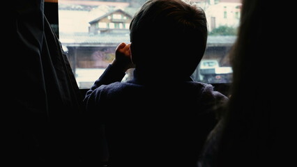 Back of pensive child observing view from train stopped at platform station. Kid traveling and...