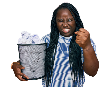 Young black woman with braids holding paper bin full of crumpled papers annoyed and frustrated shouting with anger, yelling crazy with anger and hand raised