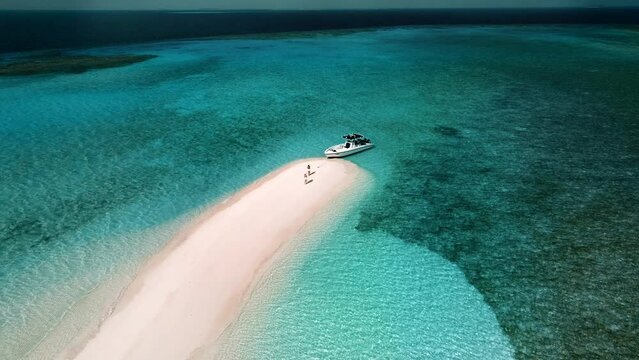 Aerial view of people walking on a white sand bank along the shoreline with Ocean view on South Ari Atoll, Maldives