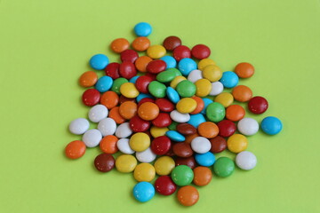 Multicolored dragee candies. A bunch of dragees on a light green background.