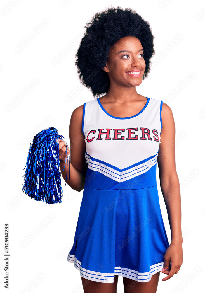 Canvas Prints Young african american woman wearing cheerleader uniform holding pompom looking away to side with smile on face, natural expression. laughing confident.