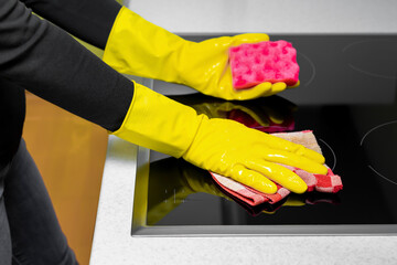 a woman in gloves wipes the hob.